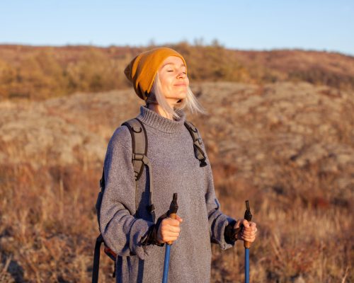 Middle aged woman, traveler backpacking nature camping, happy 40s lady with closed eyes breathing fresh air